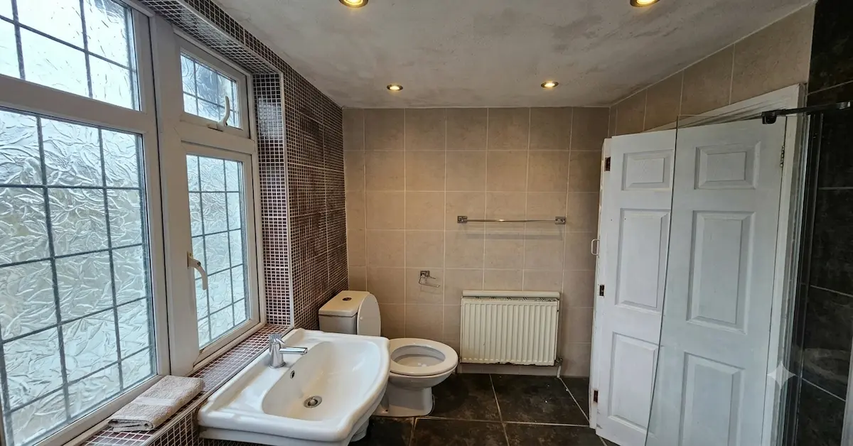 A wide-angle, landscape-oriented photograph of an older, traditional bathroom before a renovation.